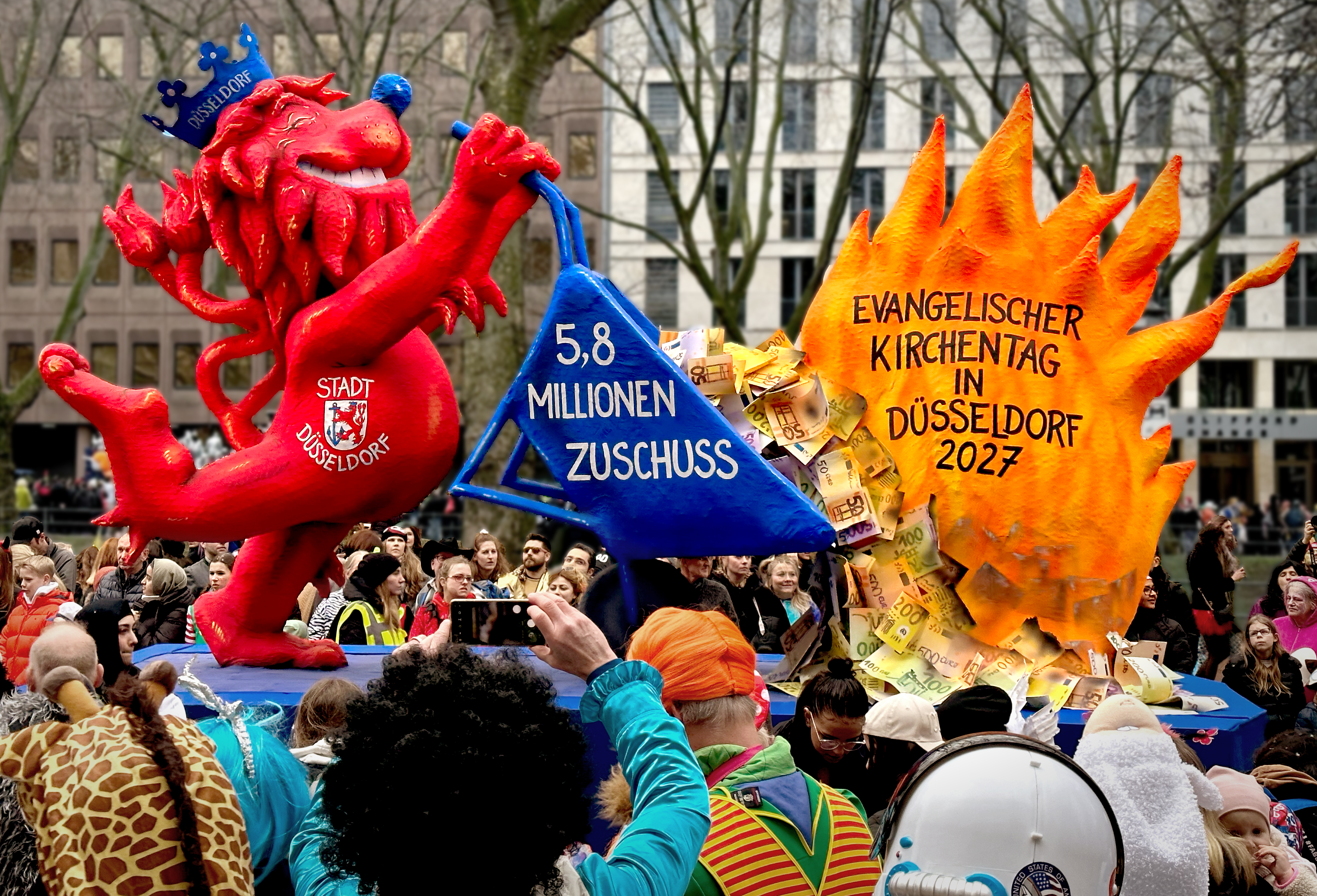 Der Düsseldorfer Löwe verbrennt symbolisch Geld für den Kirchentag