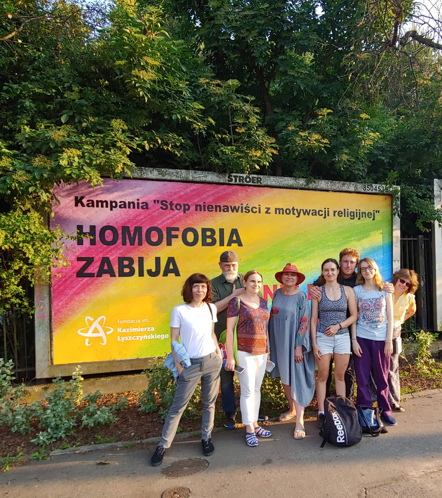 Gruppenfoto vor einem "Homophobia kills"-Plakat