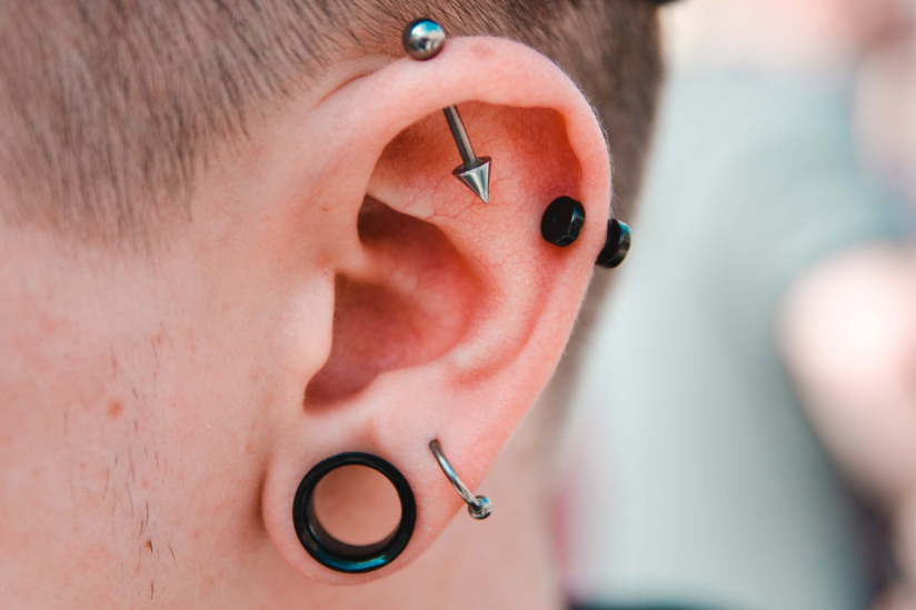 Ohr geschmückt mit einem Ohrring, zwei Piercings und einem sogenannten "Fleshtunnel"
