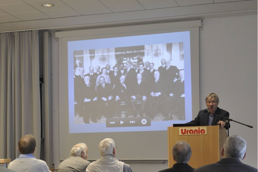 Vortragender Dr. Reinhold Lütgemeier-Davin, im Hintergrund ein Bild der Teilnehmer der deutsch-polnischen Verständigungskundgebung der Liga von 1929 