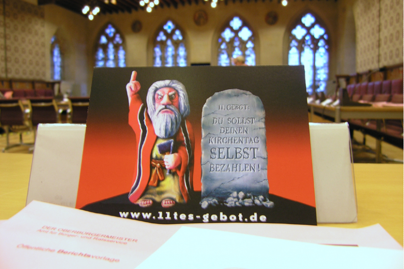 Die Kunstaktion "11. Gebot: Du sollst deinen Kirchentag selbst bezahlen" zeigt Wirkung im Rat von Münster