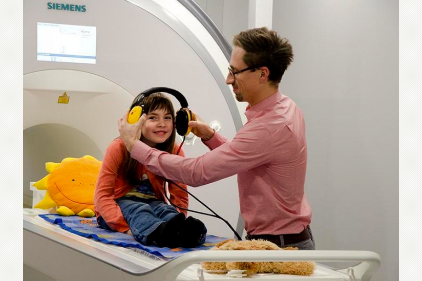 Mithilfe der Attrappe eines Hirnscanners bereitet sich eine junge Probandin auf ein Experiment vor.