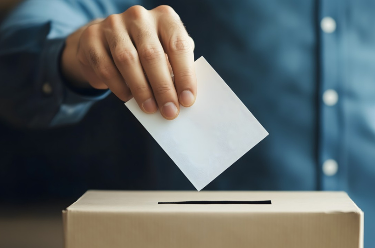 Hand mit Wahlzettel und Wahlurne 