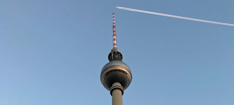 Ein Flugzeug fliegt in großer Höhe über den Berliner Fernsehturm. Der Verschwörungstheoretiker sieht hier Chemtrails.