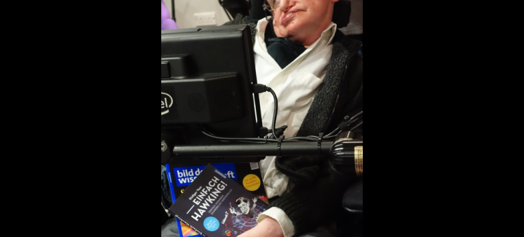 Stephen Hawking mit einem Buch über sein Werk von unserem Autor Rüdiger Vaas.