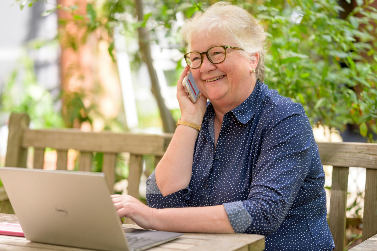 Ältere Frau mit Laptop telefoniert