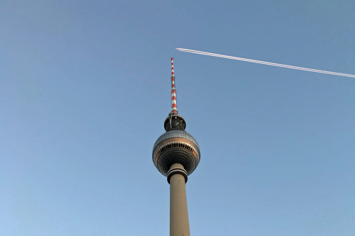 Ein Flugzeug fliegt in großer Höhe über den Berliner Fernsehturm. Der Verschwörungstheoretiker sieht hier Chemtrails.