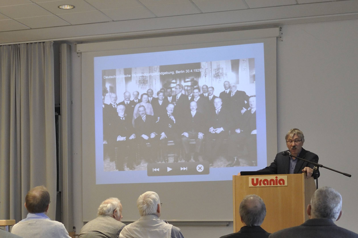 Vortragender Dr. Reinhold Lütgemeier-Davin, im Hintergrund ein Bild der Teilnehmer der deutsch-polnischen Verständigungskundgebung der Liga von 1929 